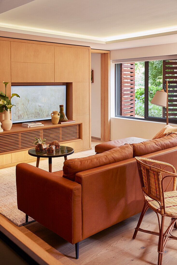 Living room with leather couch, rattan chair and wooden elements