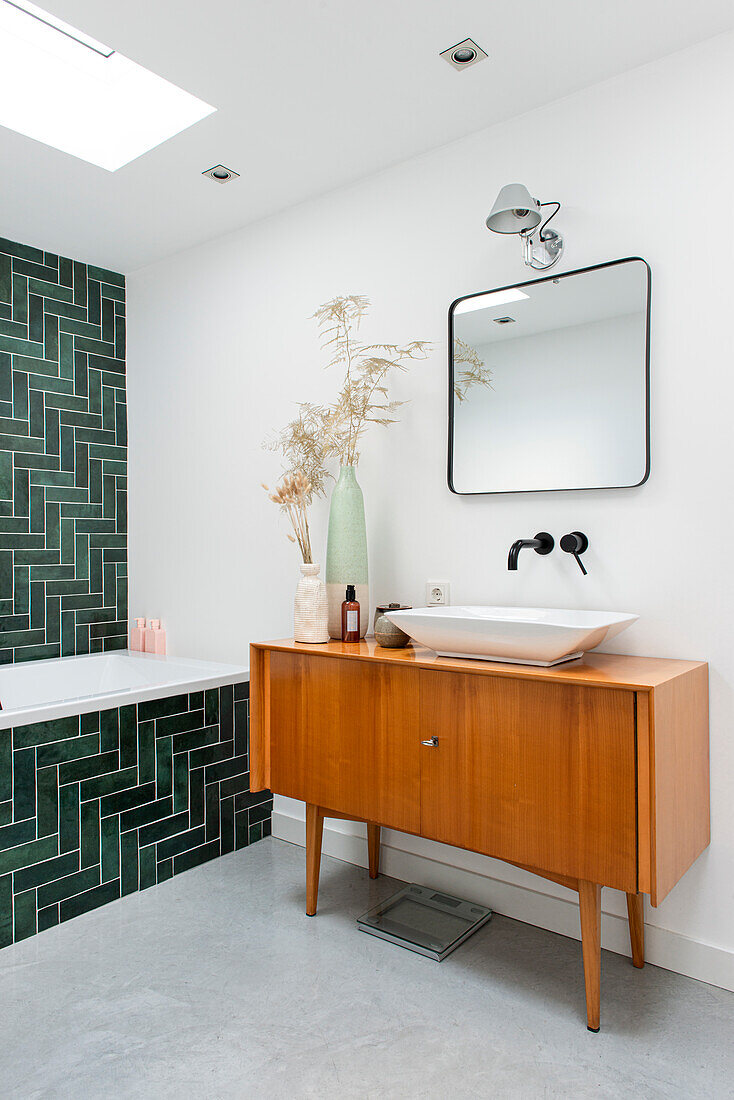 Badezimmer mit grünen Fliesen und Holzwaschtisch
