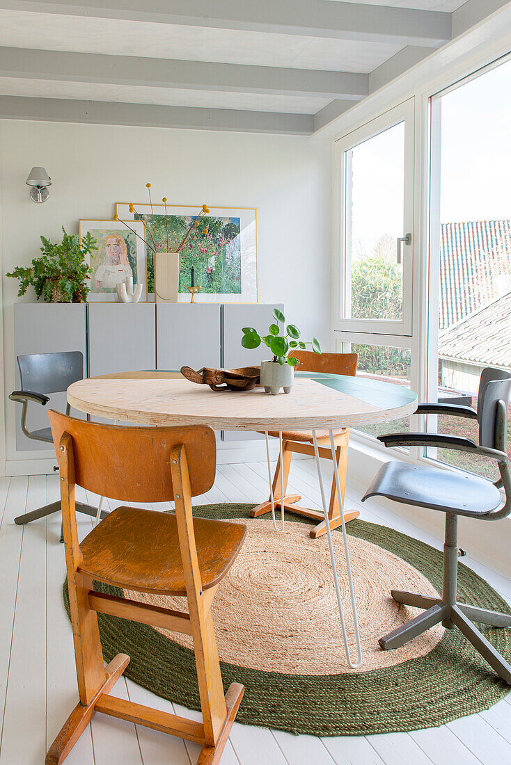 Helles Esszimmer mit rundem Tisch, Vintage-Stühlen und naturfarbenem Teppich