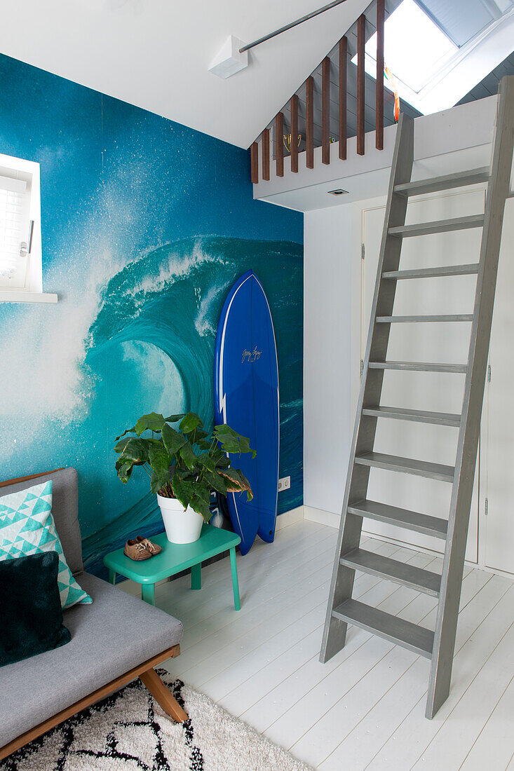 Living area with surfer flair, blue wall design, surfboard and retro sofa