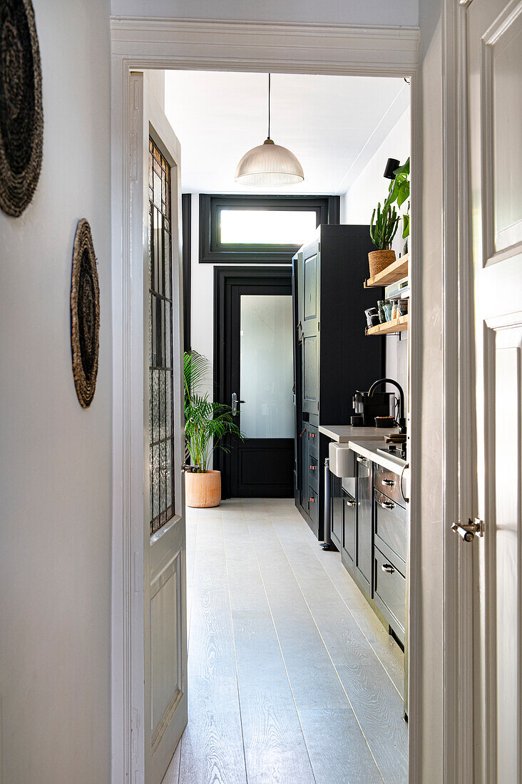 View of the kitchen with black cupboards and whitewash floorboards