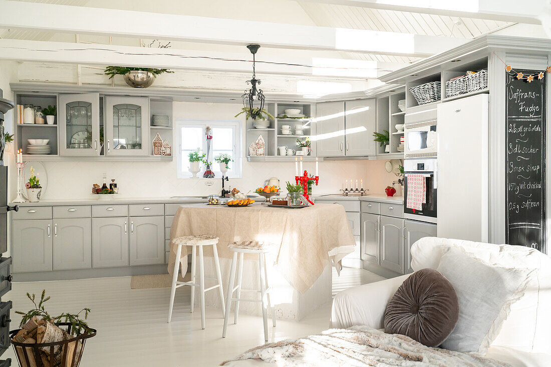 Open country kitchen in grey tones with white island and hanging lamp