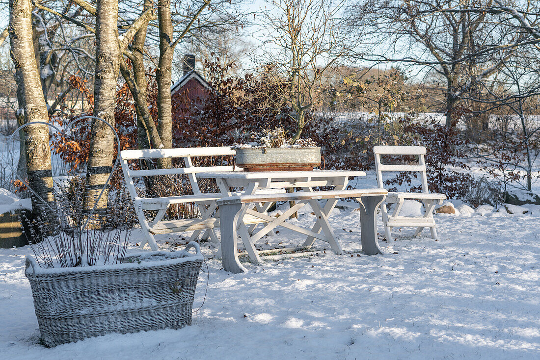 Wooden set with bench and table in the snow-covered garden