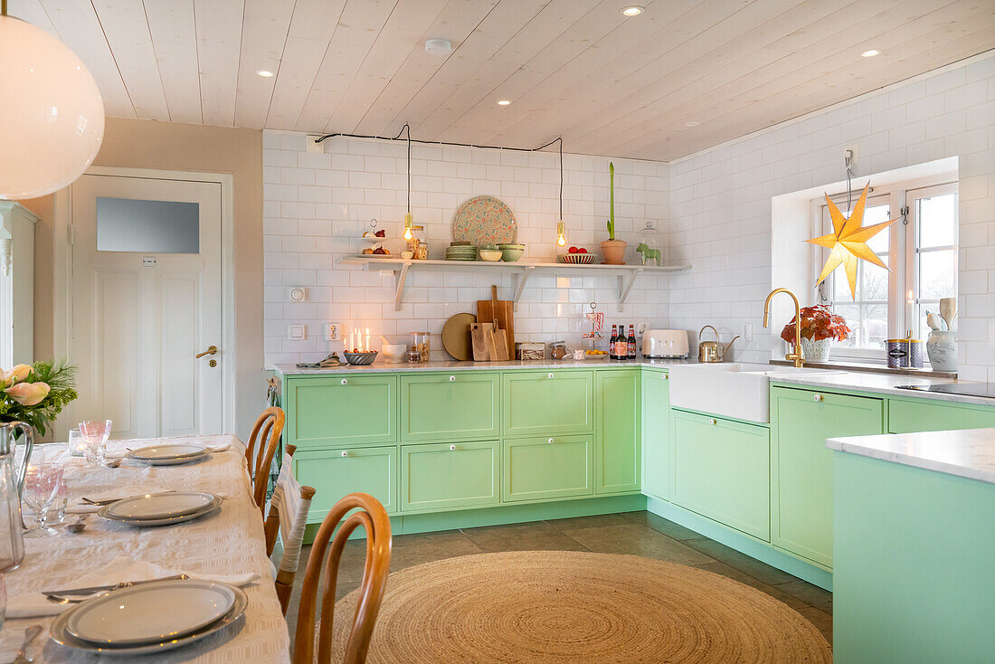 Brightly decorated kitchen with mint green cupboards and white metro tiled splashback