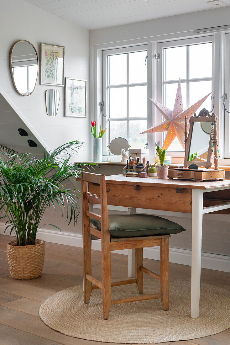 Wooden table and chair, houseplant and decorative star by the window