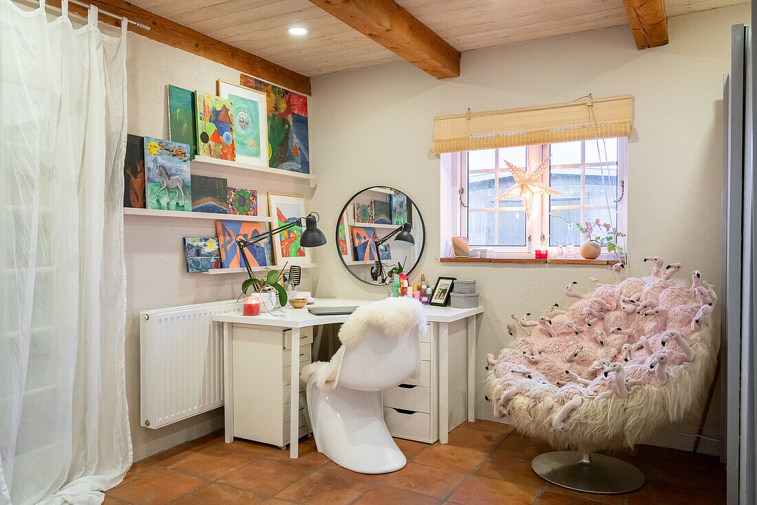 Work area with artwork, white desk and fluffy chair