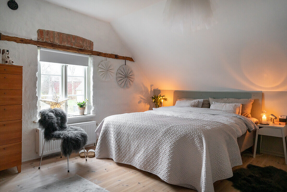 Country-style bedroom with double bed and wooden chest of drawers under a pitched roof