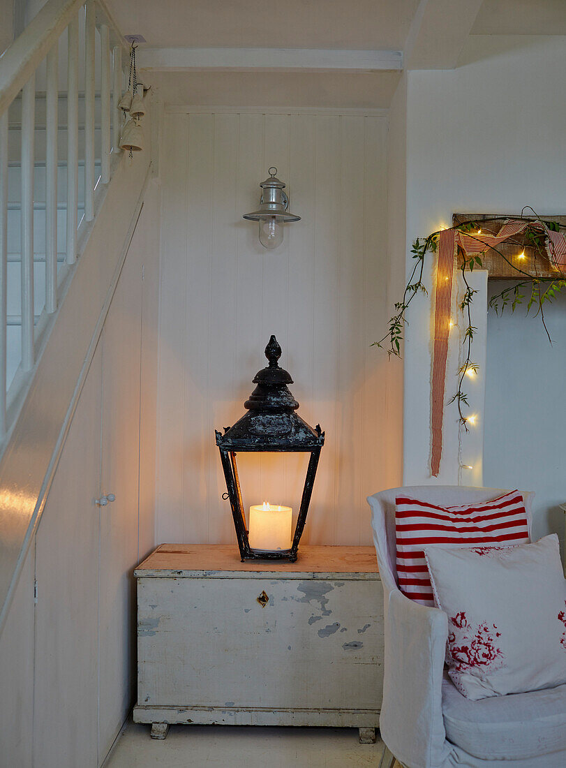 Lantern with candle on antique wooden chest next to staircase