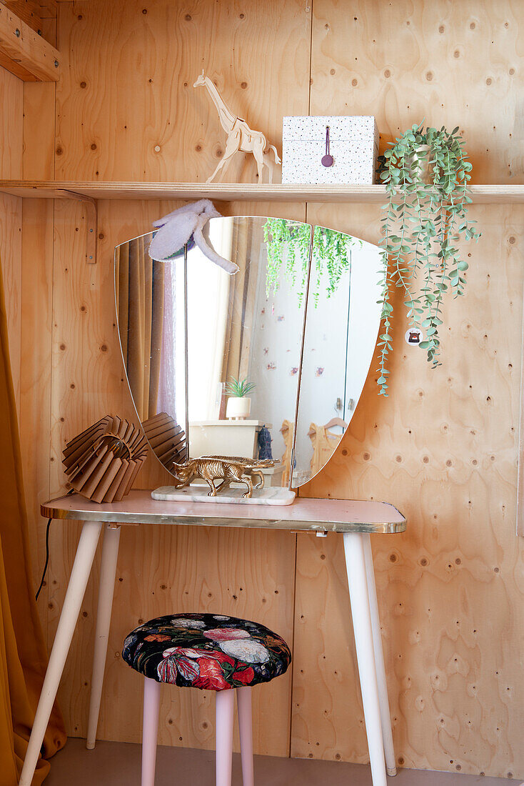 Small dressing table with mirror in room with light-colored wood paneling