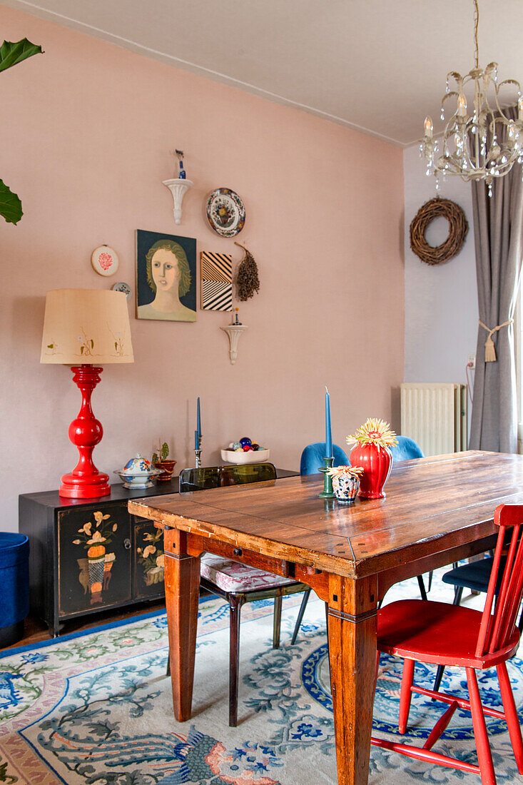 Antique wooden table and painted sideboard with red table lamp in the dining room