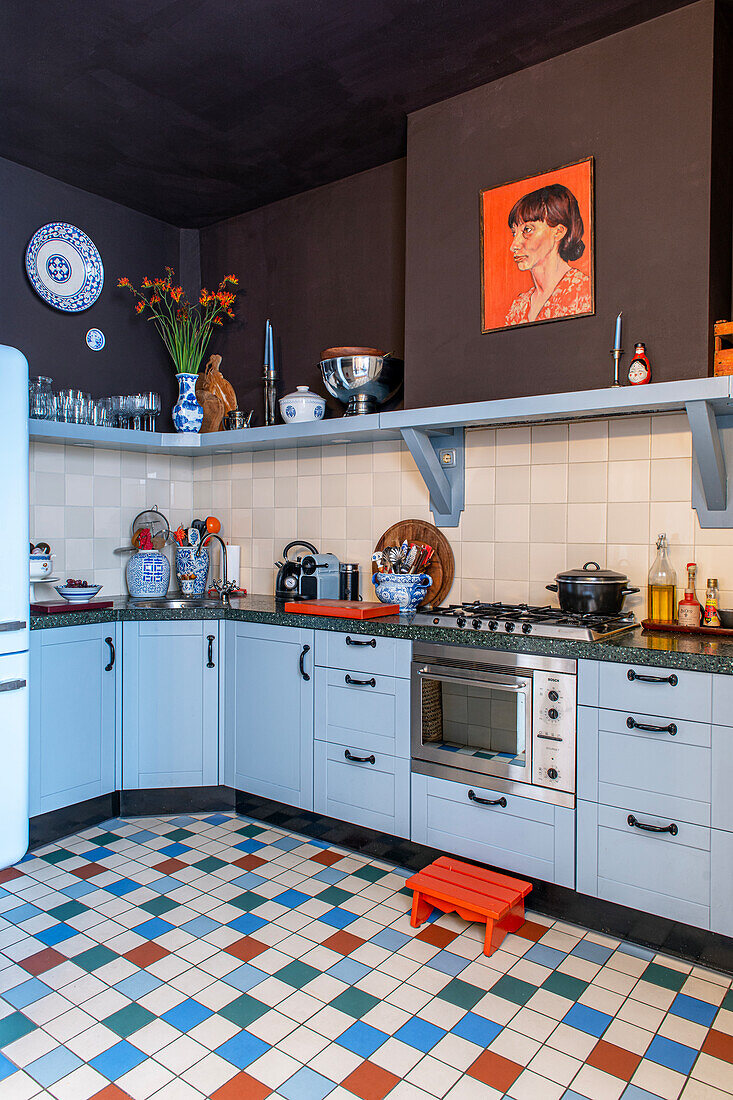 Kitchen with blue-grey base cabinets, colorful floor tiles and brown walls