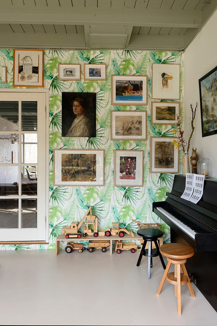 Music room with wall with tropical wallpaper and varied picture gallery