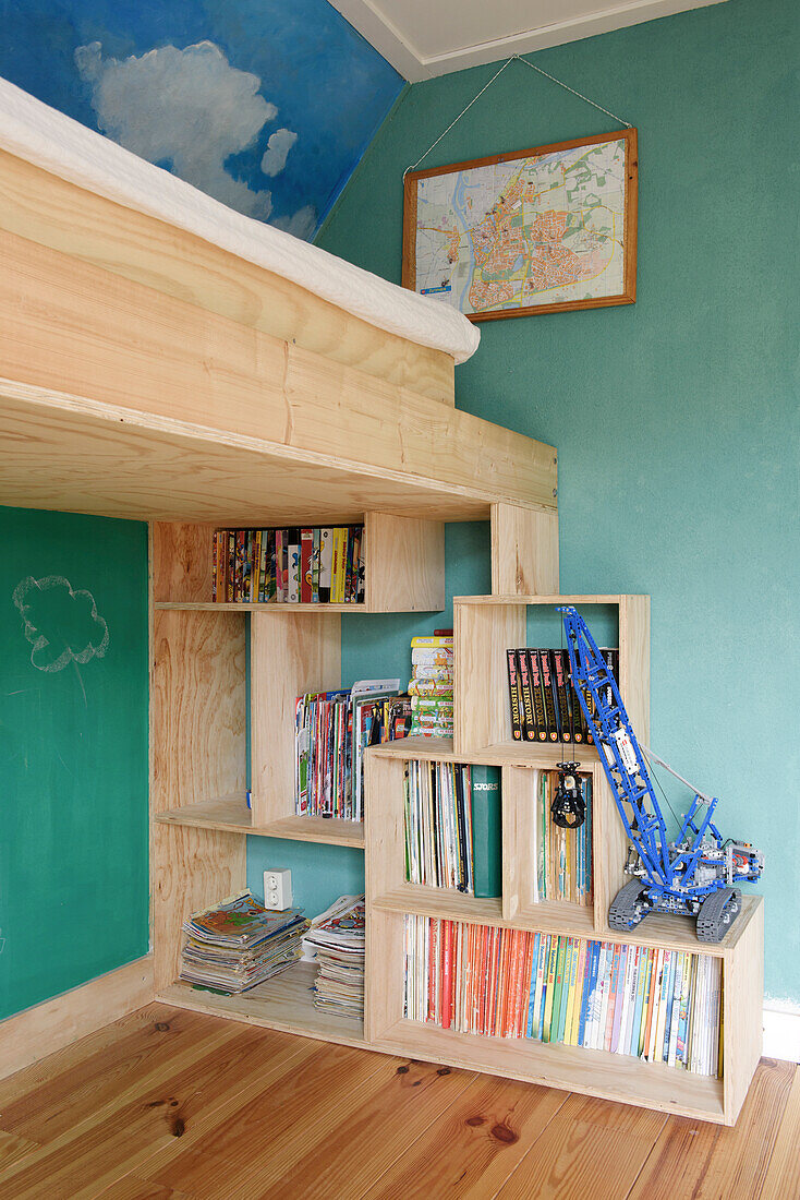 Light-colored wooden shelves, bunk bed above in children's room with green walls