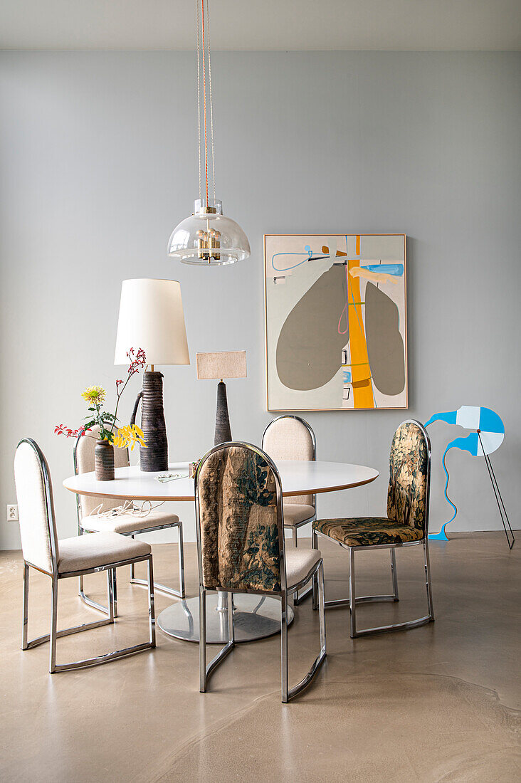 Round dining table with chrome upholstered chairs, vintage glass lamp above table
