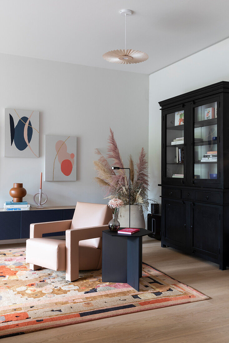 Modern living room with pink leather armchair and black display cabinet