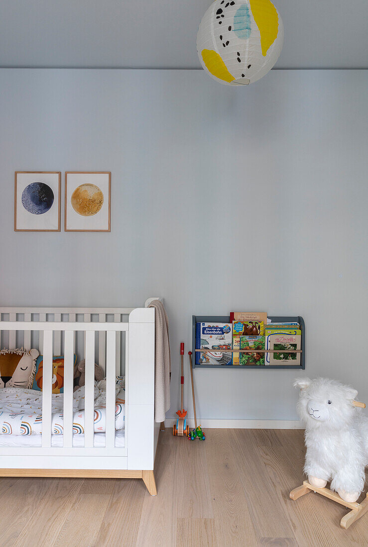 Children's room with white cot, wall shelf for books and toy llama