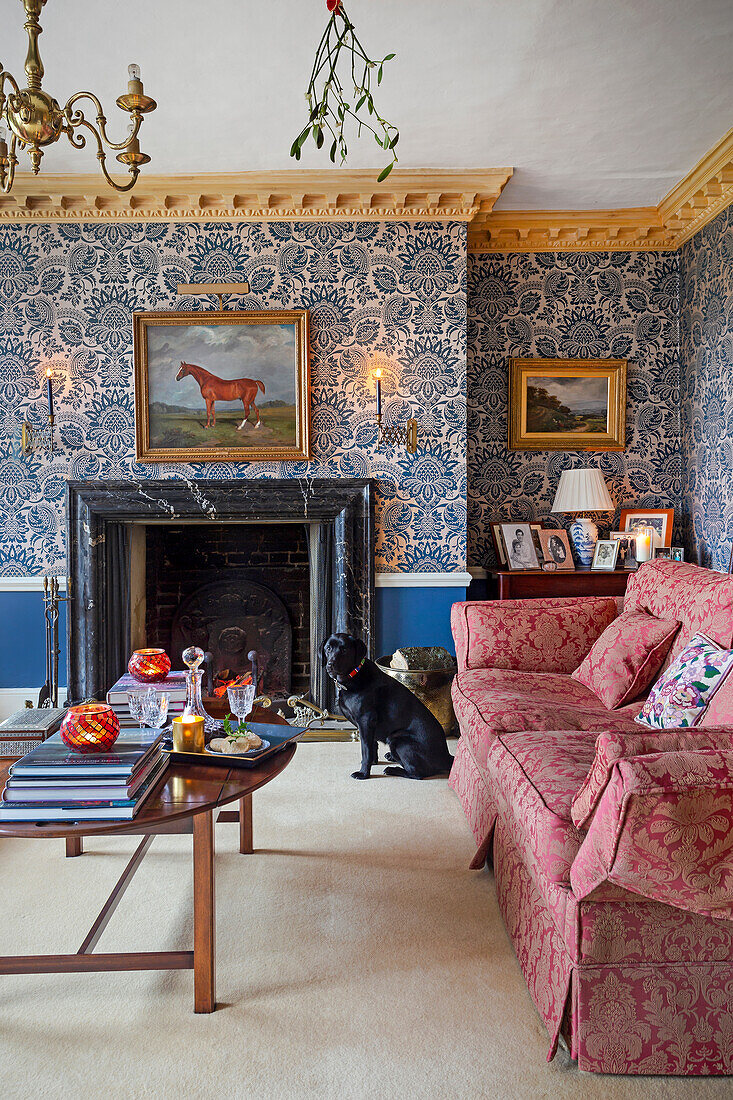 Living room with floral patterned wallpaper, fireplace and red upholstered furniture