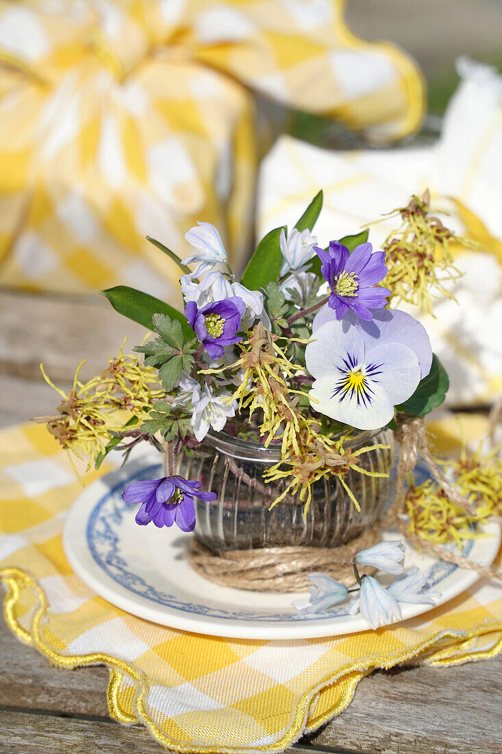 Frühlingsblumenstrauß mit Hornveilchen (Viola cornuta) und Anemonen in Glasgefäß