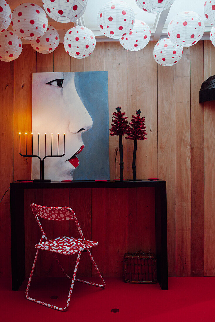 Weiße Lampions mit roten Punkten, roter Klappstuhl mit weißen Punkten, Wohnraumgestaltung mit Kunstwerk