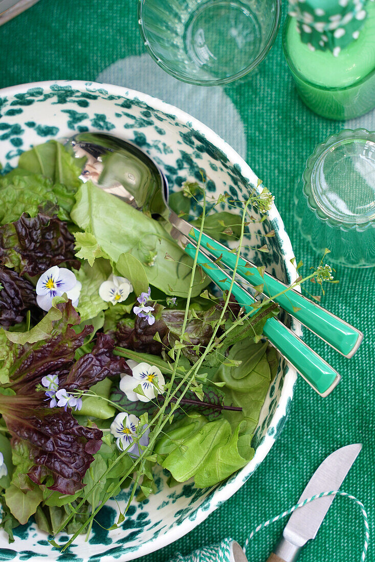 Mixed salad with edible flowers in patterned bowl