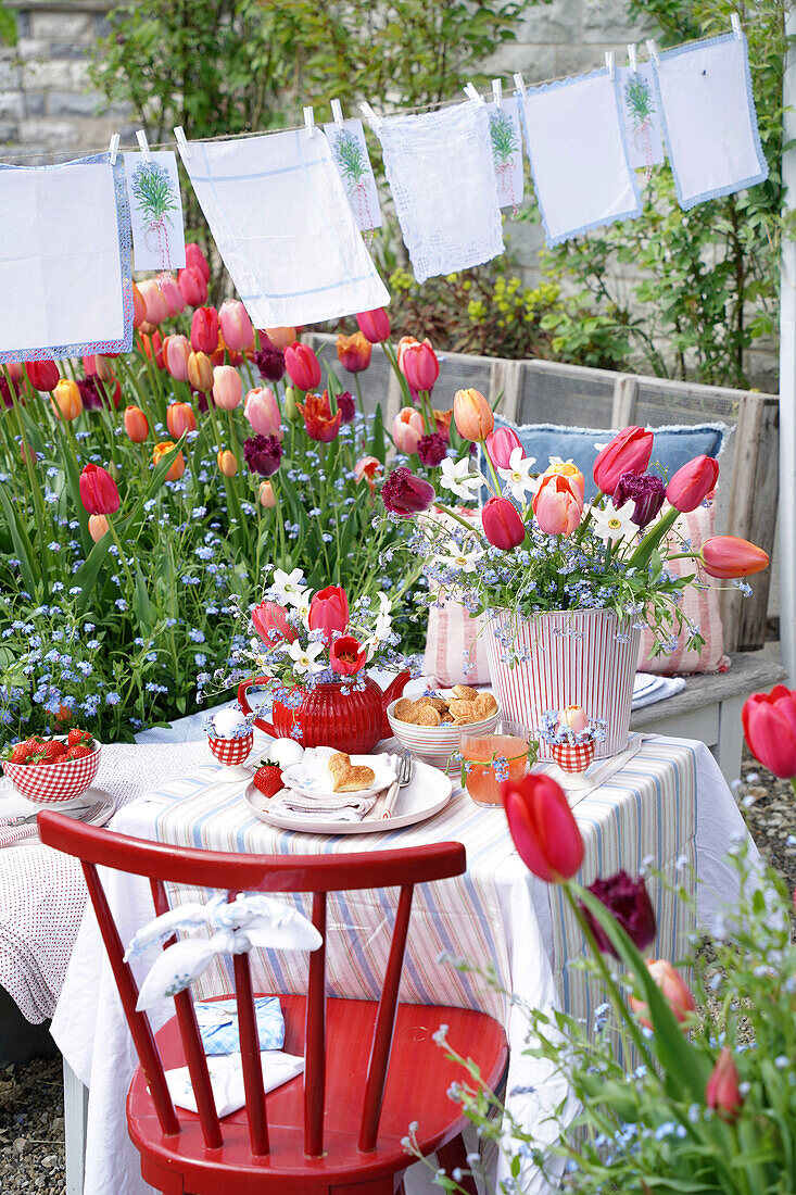 Gartentisch mit Tulpen und Kaffeegeschirr, Wäscheleine im Hintergrund