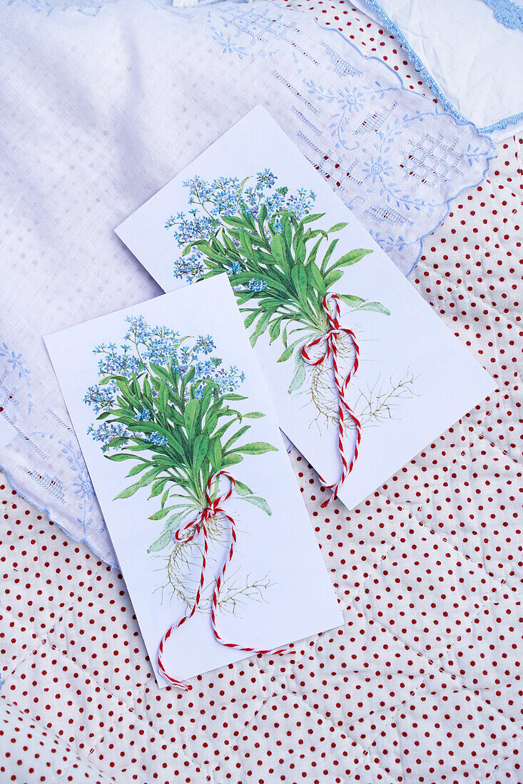 Zwei handbemalte Karten mit Blumenillustration auf gepunkteter Stoffunterlage