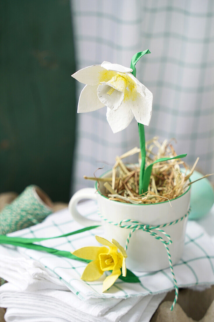 Crafted paper daffodil in cup with straw and ribbon