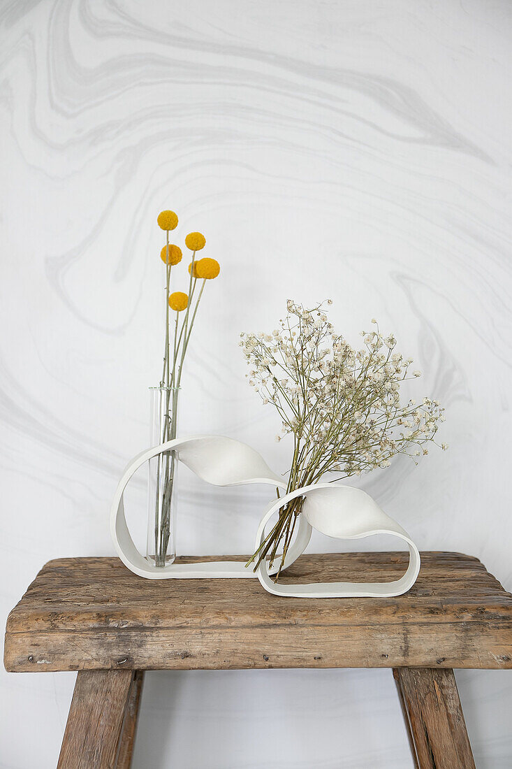 Ornate DIY vases with dried flowers on a rustic wooden stool