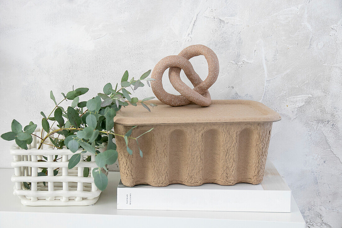 Homemade sculpture next to eucalyptus in white basket