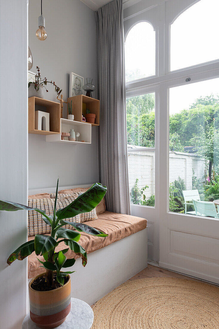 Gemütliche Leseecke mit Bank neben großem Fenster mit Ausblick auf Garten