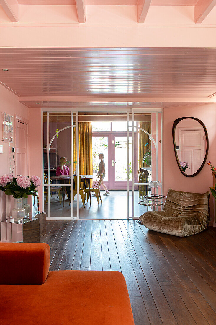 Modern living room in pink and orange tones with a view of the dining area