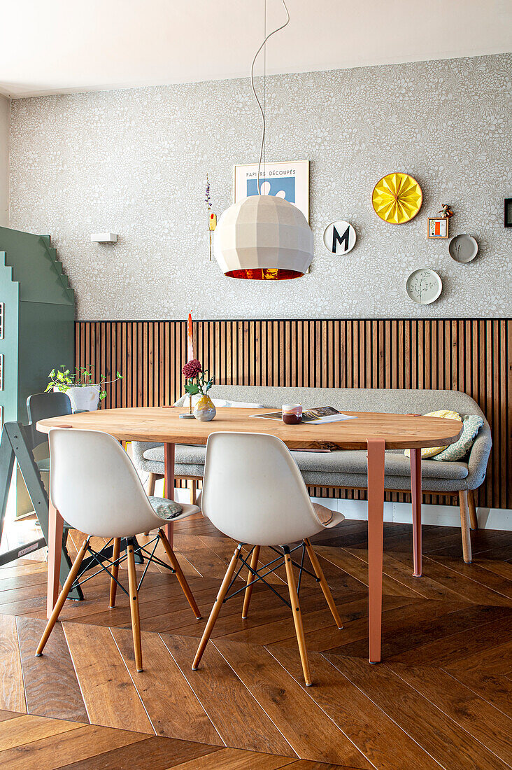 Dining area with modern chairs, wall decor and retro-style pendant light