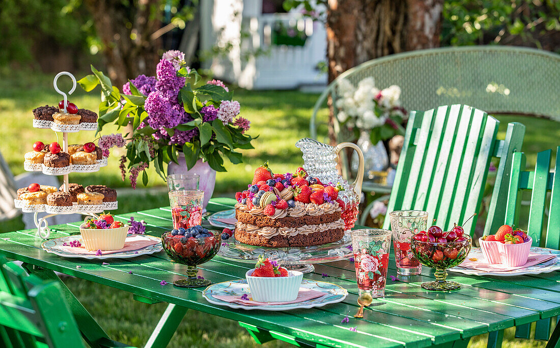 Gedeckter Gartentisch mit Kuchen und frischen Beeren im Sommer