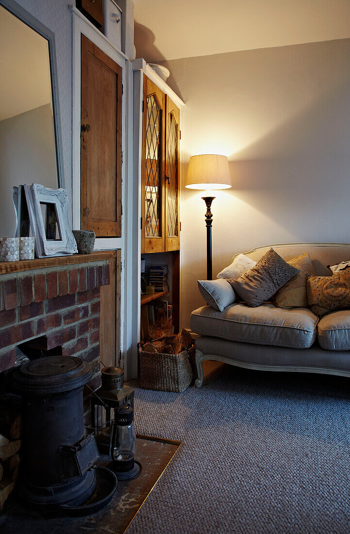 Woodburning stove in fireplace with lit lamp and sofa in Brighton home East Sussex, England, UK