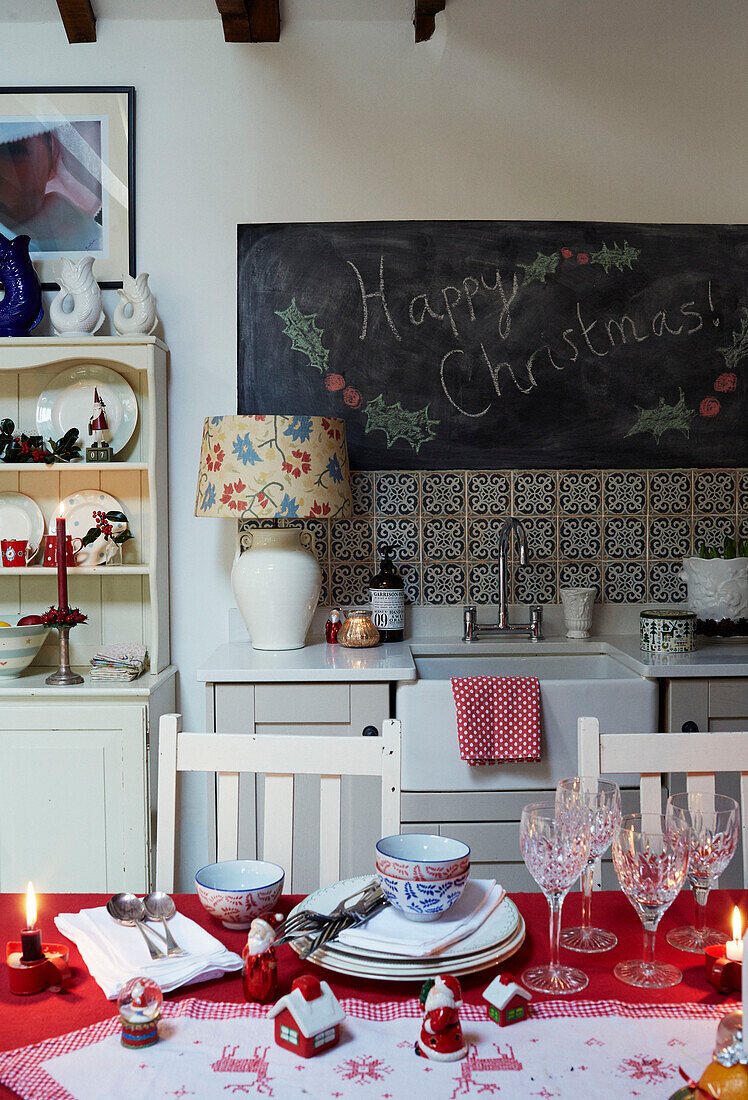 'Happy Christmas' on blackboard above sink with glasses and crockery on table