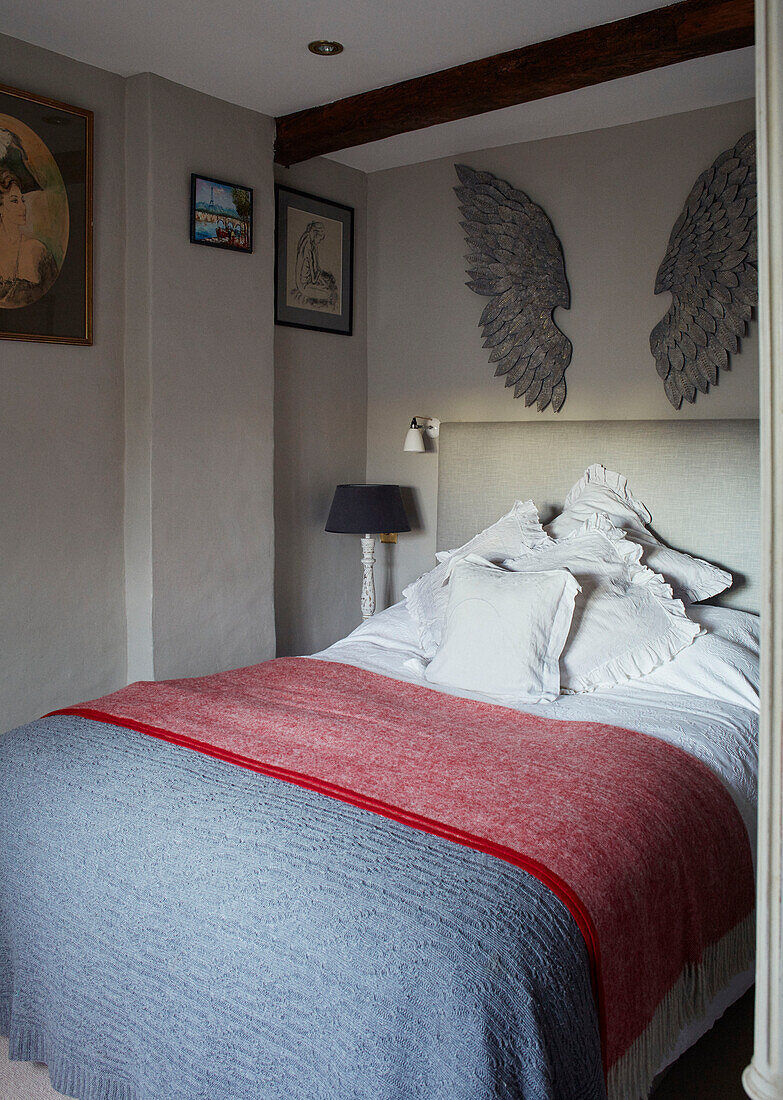 Engelsflügel über einem Doppelbett mit Leinenkissen und pastellblauen und rosa Bezügen