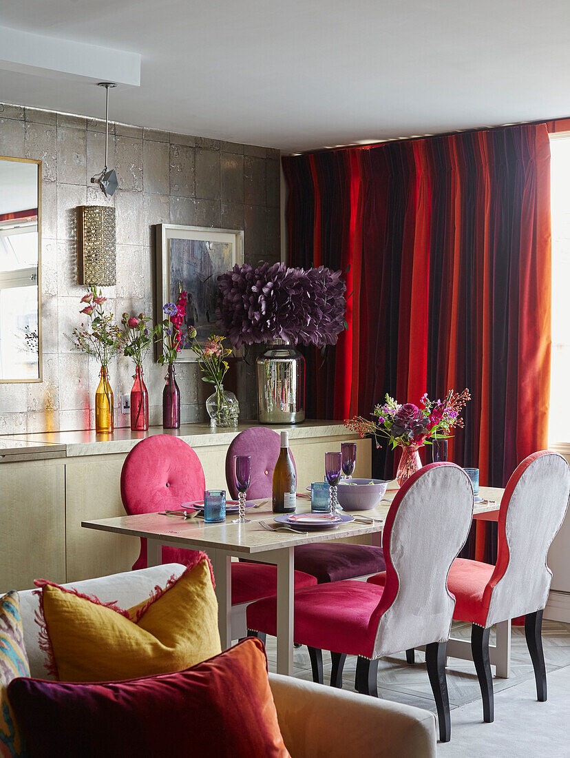 Pinkfarbene Esszimmerstühle am Tisch mit Vorhängen in Rottönen Londoner Wohnung, UK
