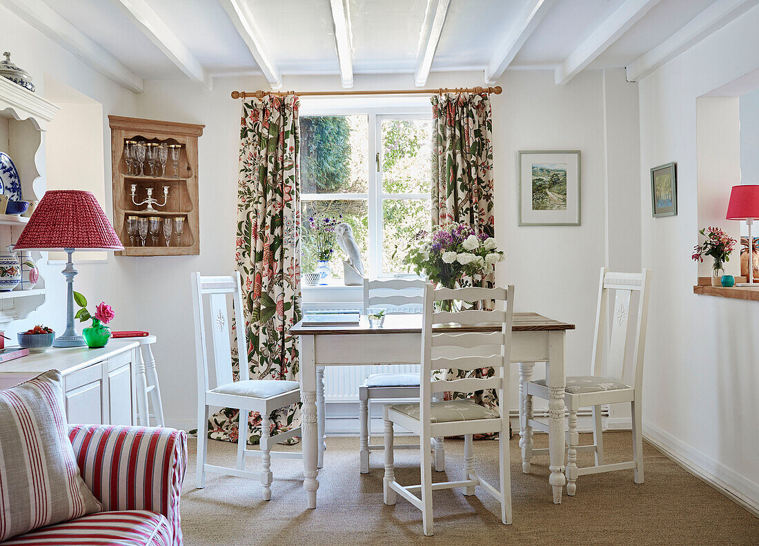 Floral curtains and corner cabinet with dining table and chairs in, UK cottage