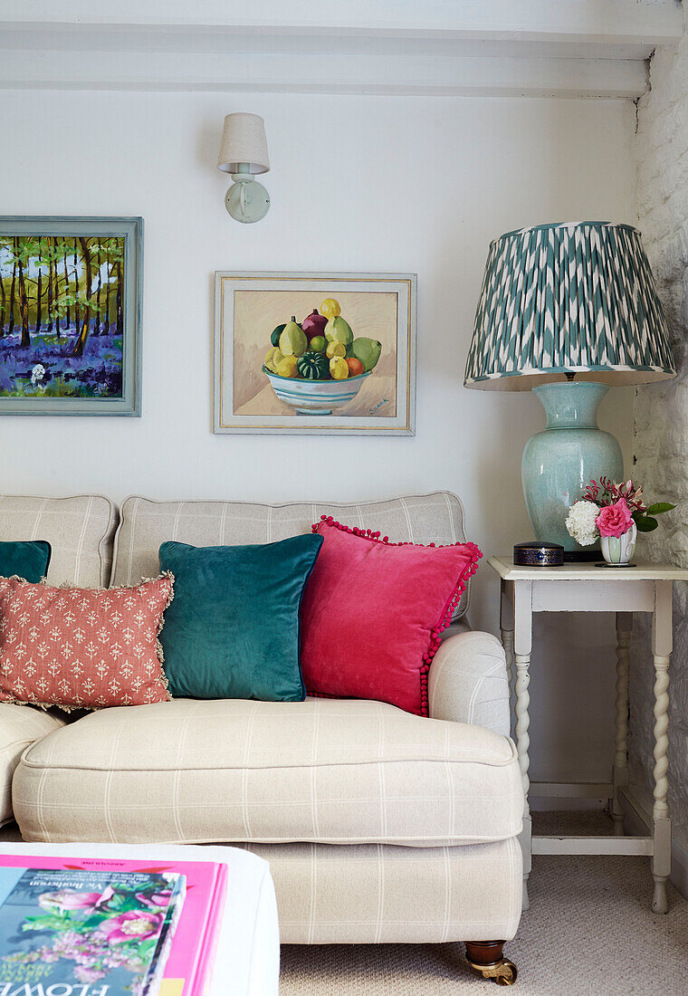 Gerahmtes Kunstwerk über dem Sofa mit Samtkissen und Lampe in einem britischen Landhaus
