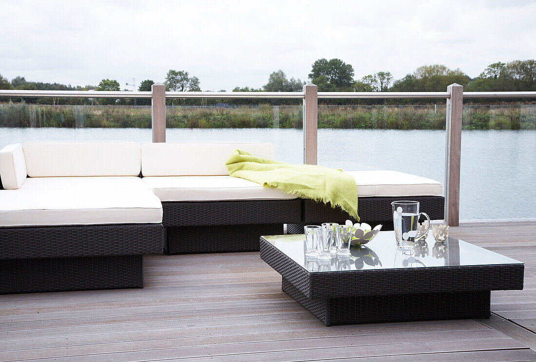 Gartenmöbel auf einer überdachten Terrasse mit Blick auf einen See