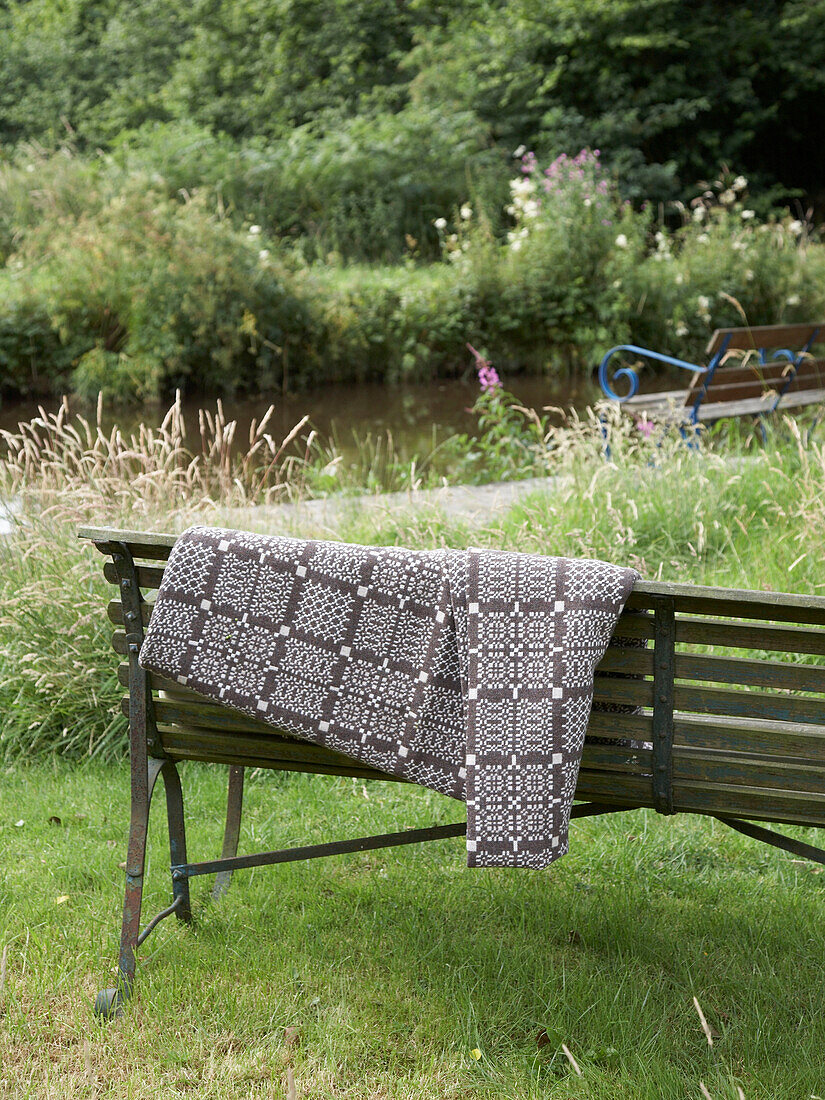 garden bench with blanket and cushion