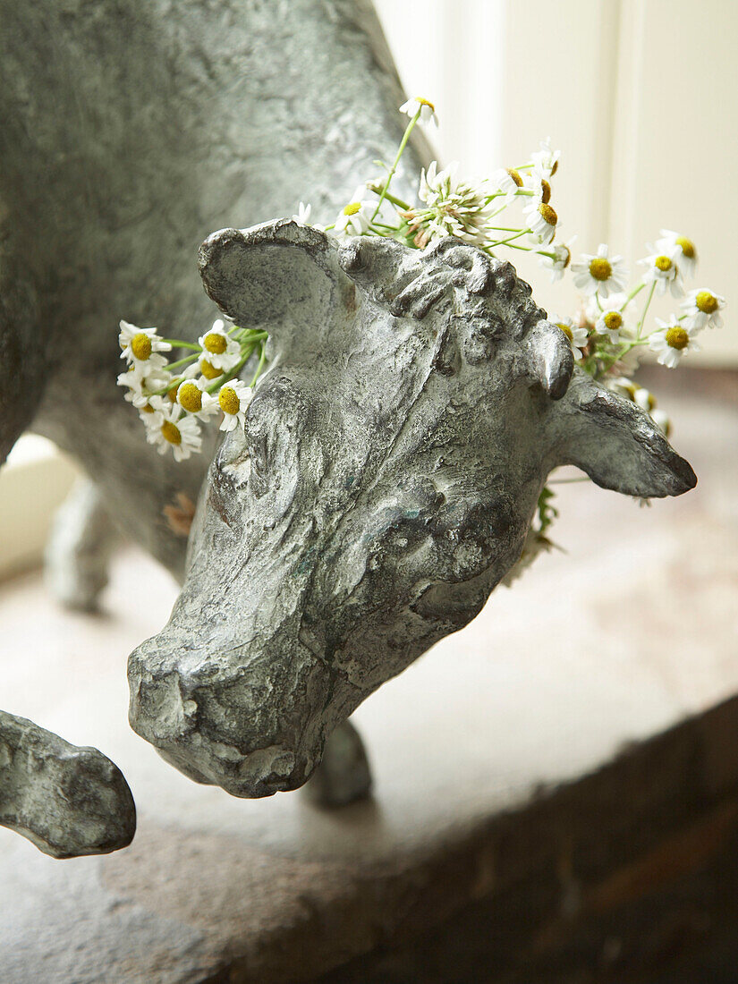 Sculpture of a cow draped in daisies