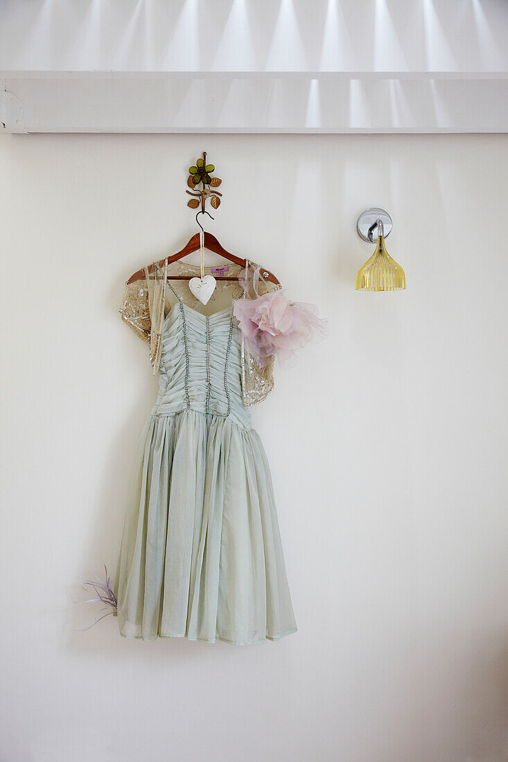 Vintage-Kleid und Leuchte hängen an einer weißen Wand in einem Haus in Brighton, East Sussex, England, UK