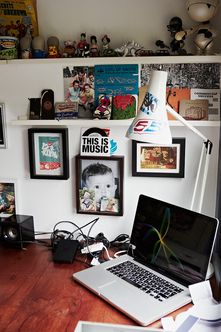 Artwork and ornaments with desk lamp and laptop computer on desk in Colchester studio Essex, England, UK