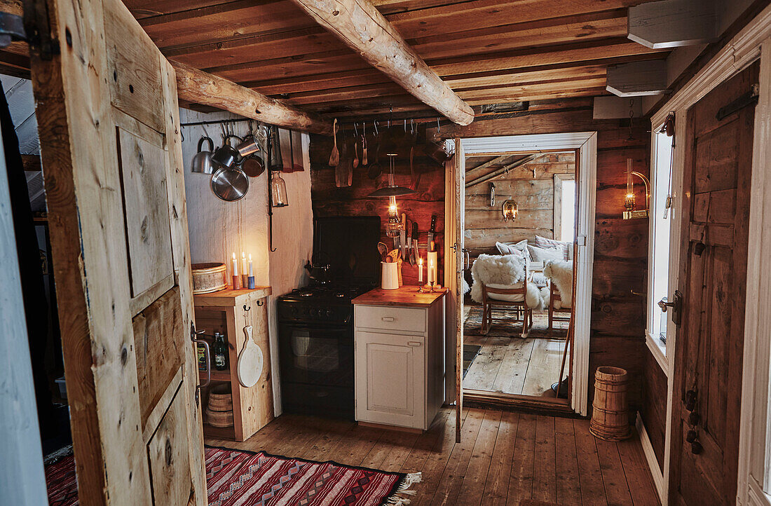 Blick durch die Küche zum Wohnzimmer in einer Holzhütte mit Kerzenlicht in den Bergen von Sirdal, Norwegen