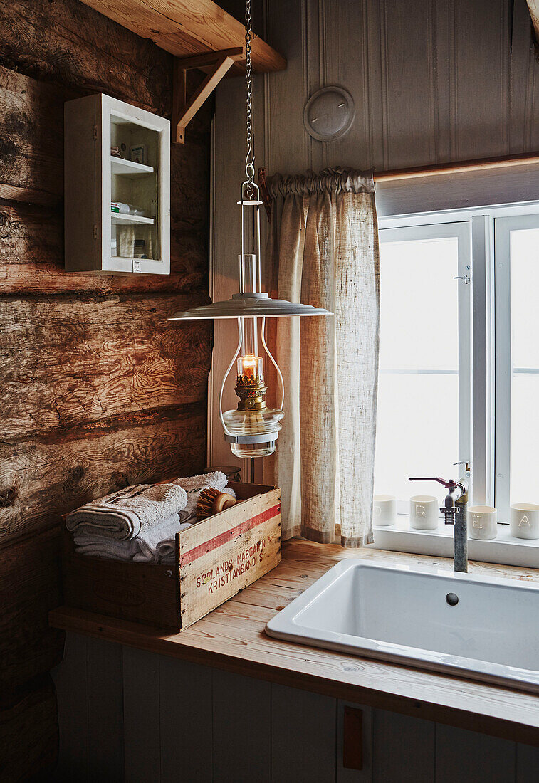 Waschbecken im Badezimmer mit Laterne in einer Holzhütte in den Bergen von Sirdal, Norwegen