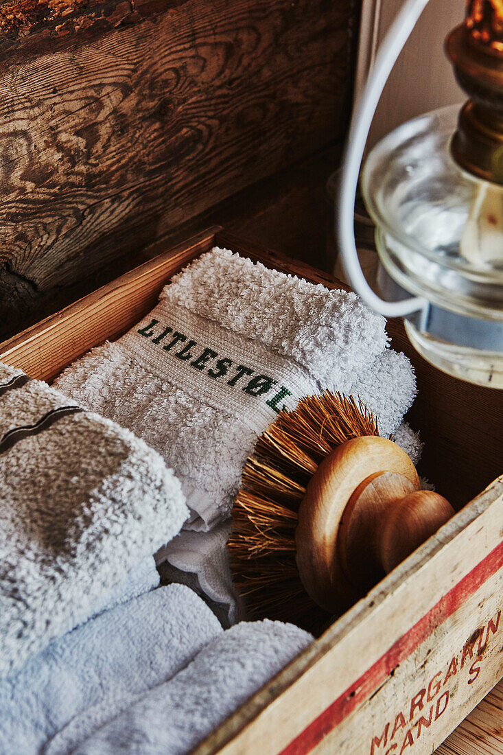 Detail eines Badezimmers mit Öllaterne und Kiste mit Handtüchern und Waschlappen in einer Holzhütte in den Bergen von Sirdal, Norwegen