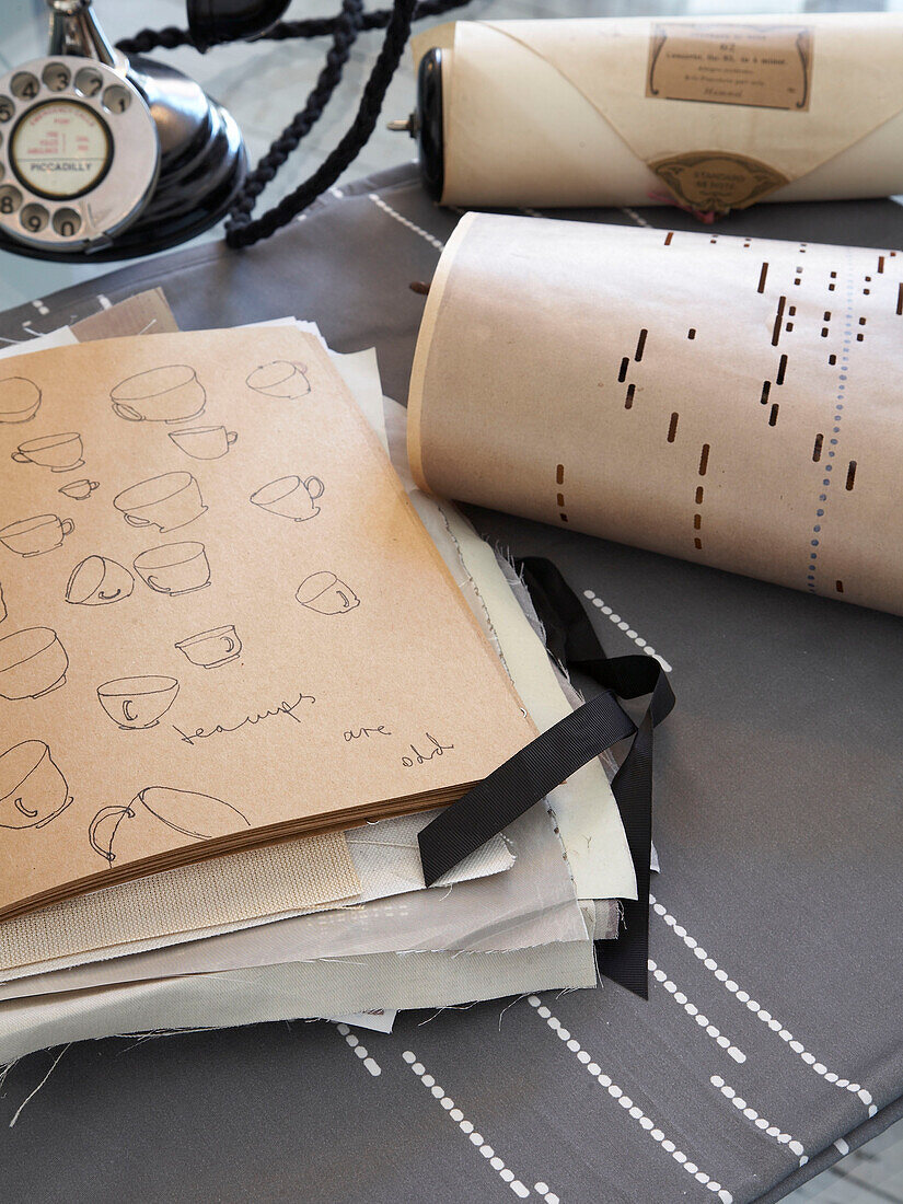 Skizzenbuch mit Stoffmustern und Vintage-Telefon auf dem Tisch in einem Haus in Winchester, Hampshire, UK