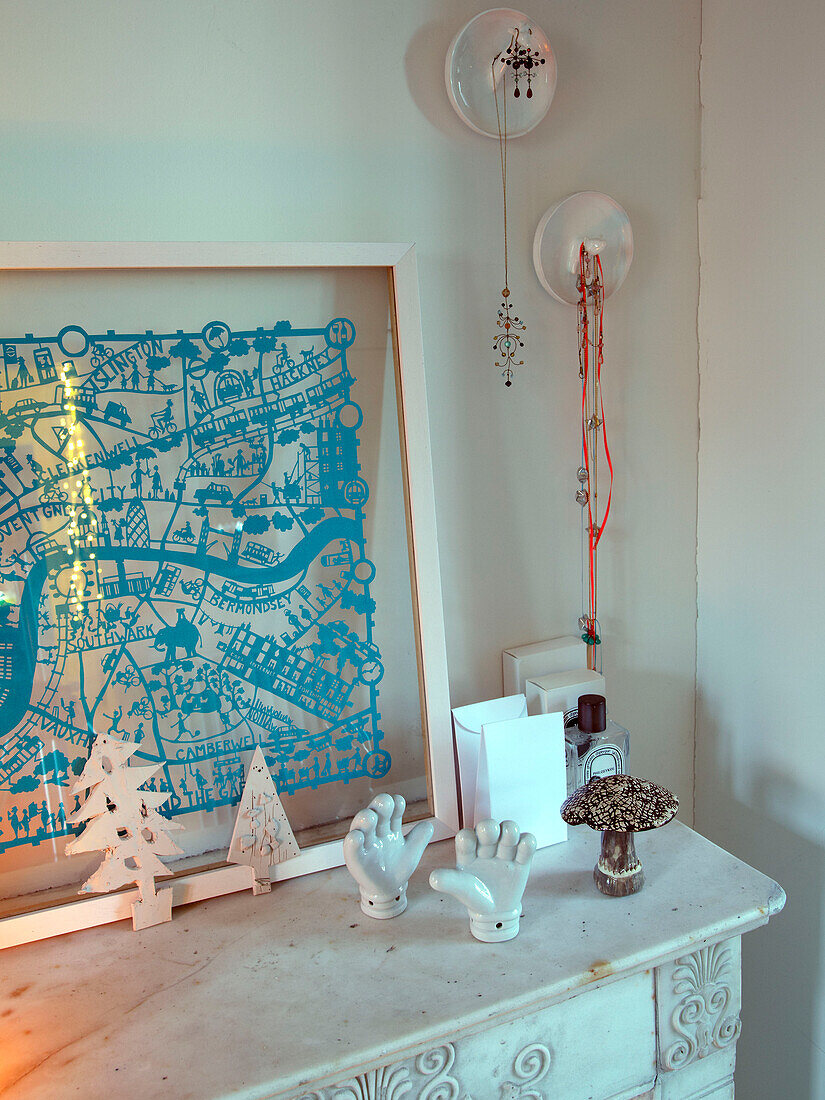 Weiße Keramikornamente mit türkisfarbenem Kunstwerk auf dem Kaminsims in einem Familienhaus in Frankreich