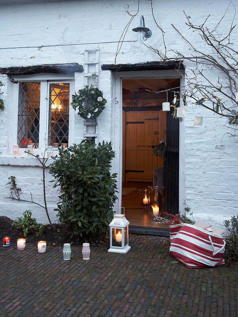 Lit candles and lantern at open door of Herefordshire cottage, England, UK